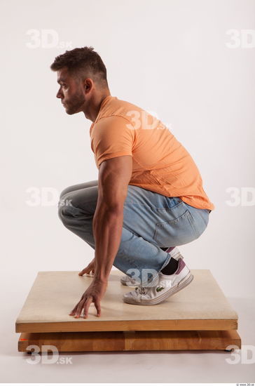 Kneeling pose orange thsirt light blue jeans of bodybuilder Harold