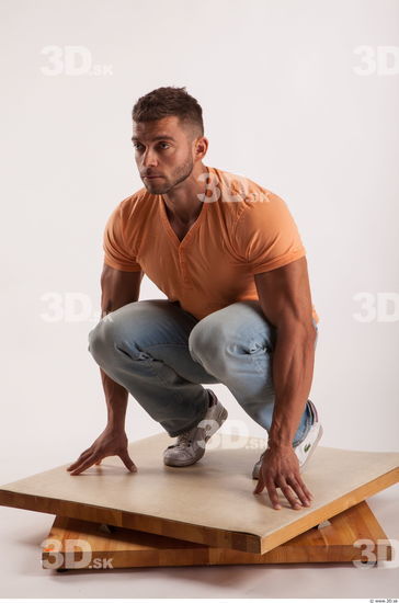 Kneeling pose orange thsirt light blue jeans of bodybuilder Harold