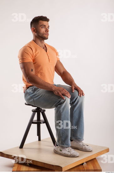 Sitting pose orange thsirt light blue jeans of bodybuilder Harold