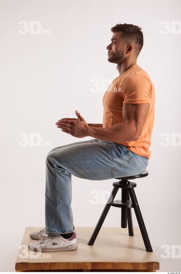 Sitting pose orange thsirt light blue jeans of bodybuilder Harold