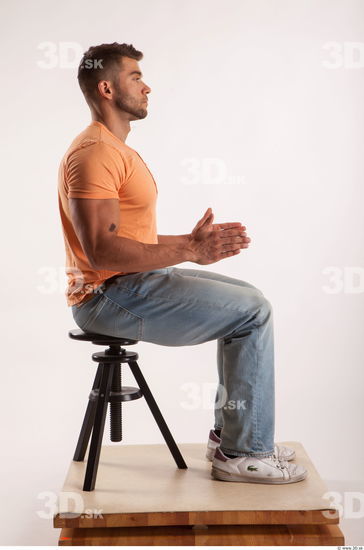 Sitting pose orange thsirt light blue jeans of bodybuilder Harold