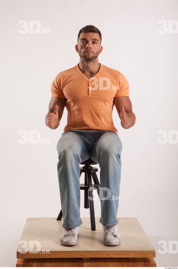 Sitting pose orange thsirt light blue jeans of bodybuilder Harold