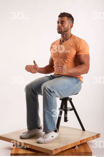 Sitting pose orange thsirt light blue jeans of bodybuilder Harold